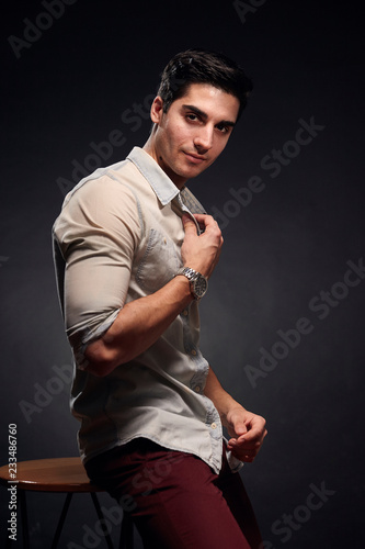 one young handsome man, handsome model, 20-29 years old, posing in studio, photo shoot. black background. casual clothes. wearing jeans shirt.