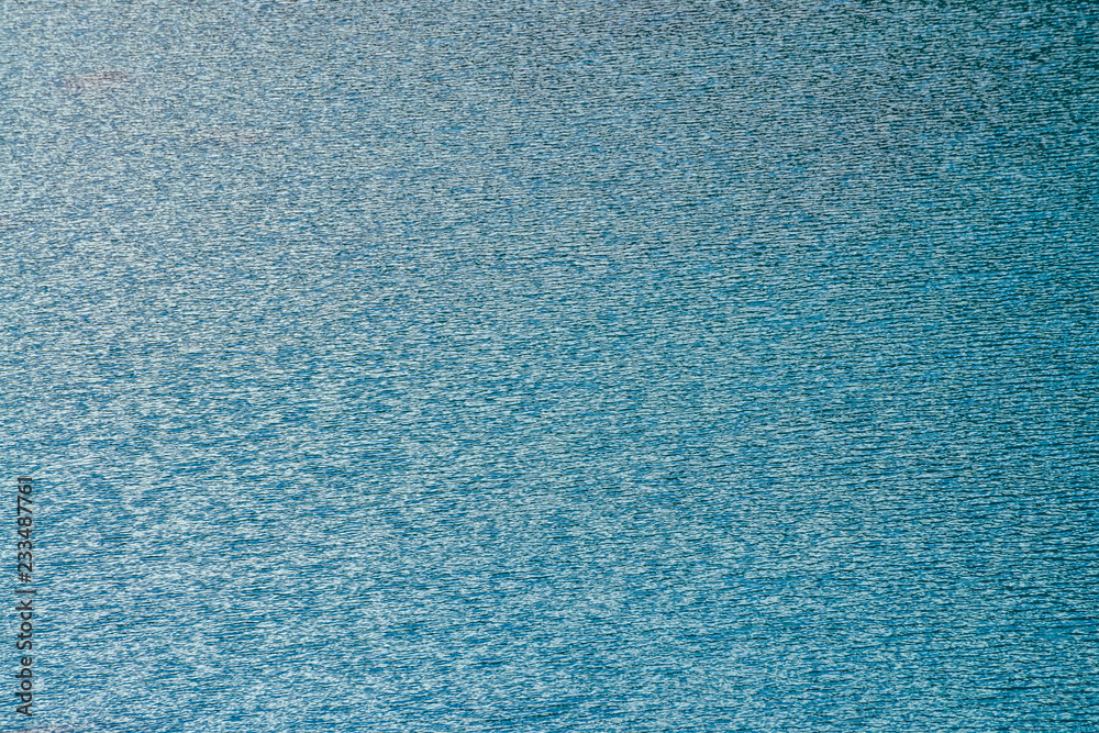 Amazing textured background of calm cobalt clean water surface in evening. Sunshine reflected in mountain lake close up. Beautiful ripples on shiny blue water in morning. Wonderful relax texture. Amazing textured background of calm cobalt clean water surface in evening. Sunshine reflected in mountain lake close up. Beautiful ripples on shiny blue water in morning. Wonderful relax texture.