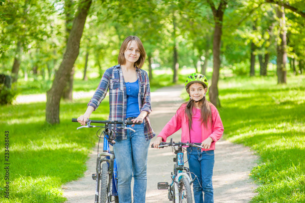 Obraz premium Mom and daughter are cycling in the park together