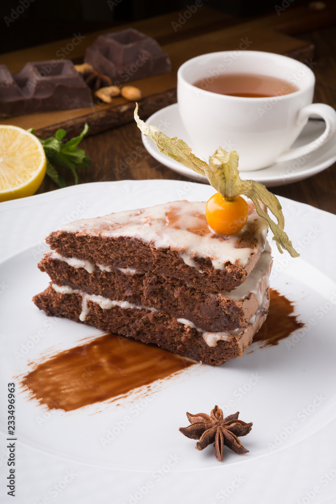Slice of chocolate cake served with cupt tea and mint Slice of chocolate cake served with cupt tea and mint