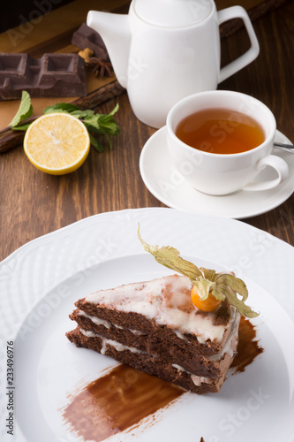 Slice of chocolate cake served with cupt tea and mint
