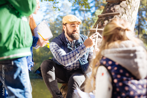 Ecological issues. Smart adult man speaking about windmills while sitting in front of pupils