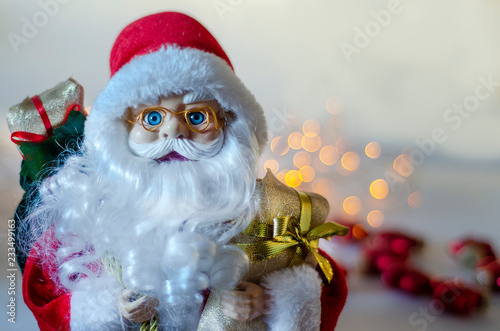 toy under the Christmas tree soft elegant Santa with a bag of gifts behind him, on a white background © Julia