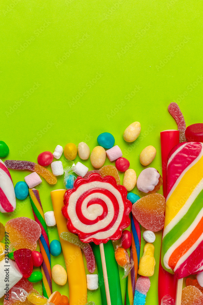 Fototapeta premium Colorful candies on green background