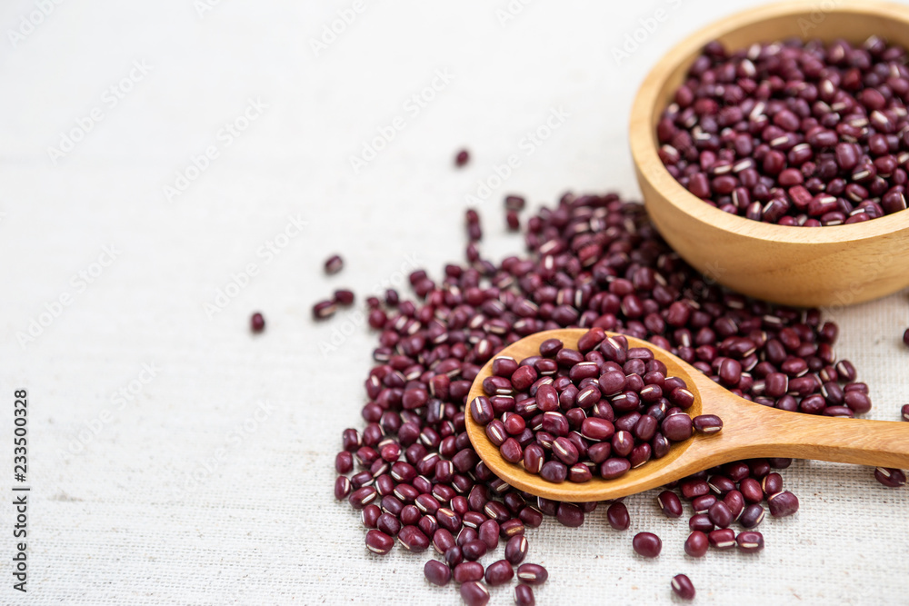 Red beans in wooden spoon and round wooden bowl on canvas texture background Red beans in wooden spoon and round wooden bowl on canvas texture background