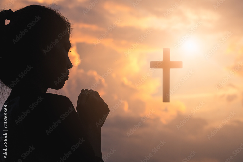 Silhouette of young woman praying with a cross at sunrise, Christian Religion concept background. Silhouette of young woman praying with a cross at sunrise, Christian Religion concept background.