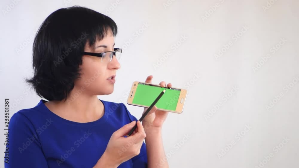 Brunette girl demonstrates the green screen of the smartphone on a white background. Girl businessman tells the information, showing the screen of the smartphone. Brunette girl demonstrates the green screen of the smartphone on a white background. Girl businessman tells the information, showing the screen of the smartphone.