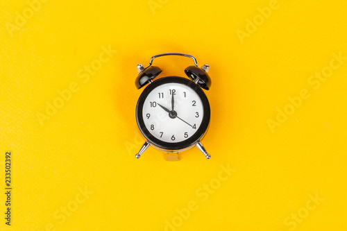 Alarm clock on bright yellow background close up