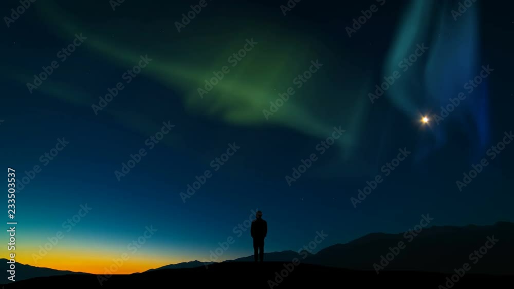 The man standing on a mountain against the sky with a northern light. time lapse