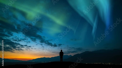The man standing on a mountain against a sunrise and northern light. time lapse