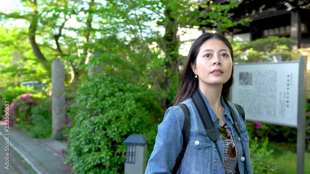 beautiful woman walking past the green garden beside the road in a sunny day beautiful woman walking past the green garden beside the road in a sunny day
