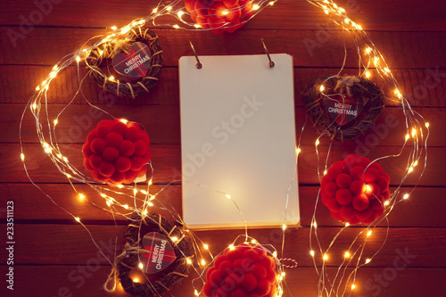 Christmas  background.notepad, heart with the inscription Christmas , pompoms and shining garland on a wooden background. Winter holiday background. Festive  mood