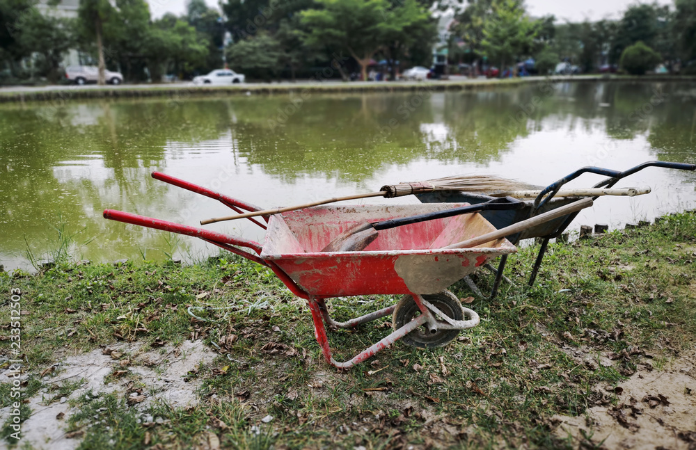 High Angle View of Wheelbarrows with Gardening Equipment by the Pond High Angle View of Wheelbarrows with Gardening Equipment by the Pond