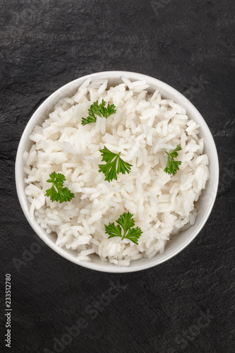 An overhead photo of a bowl of cooked white long rice, shot from the top on a dark background with copy space