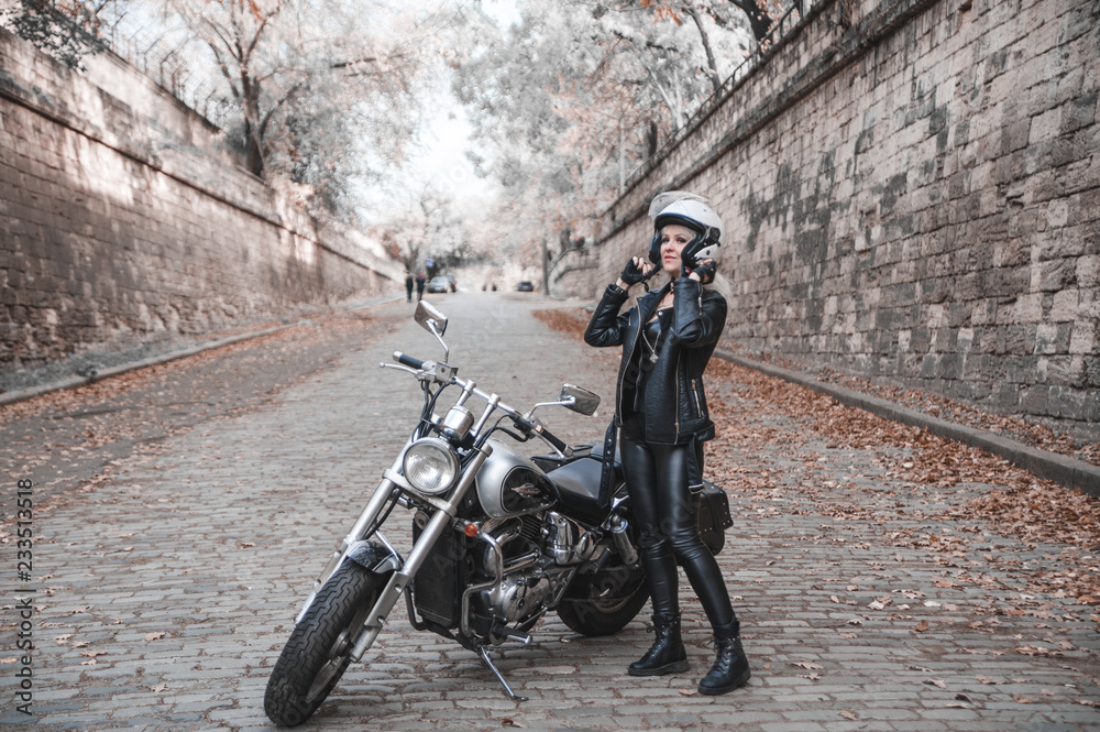 Stylish blond woman with motorcycle outdoor.
