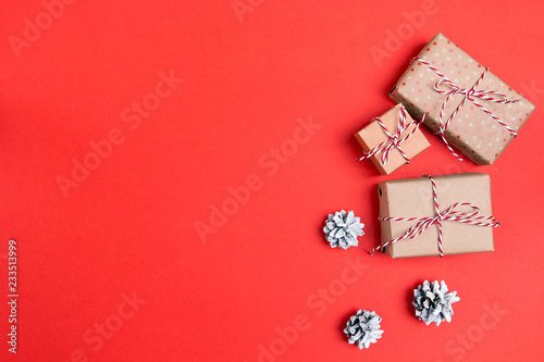 Gift boxes with pine cones on red background and space for text. Christmas background