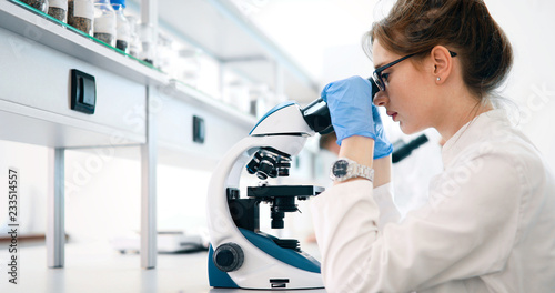 Young scientist looking through microscope in laboratory