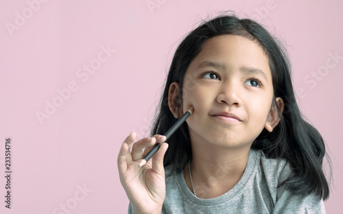 Little girl holding a pencil and thinking something