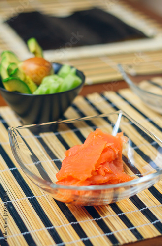 Closeup of bowls with salmon, avocado and cucumber cut ready to prepare sushi