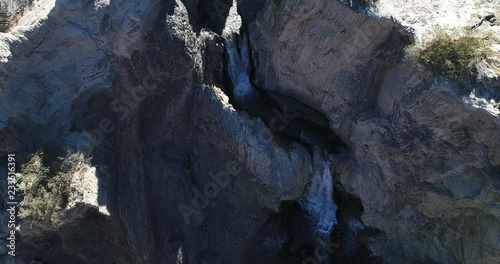 Aerial drone scene from senital to front view, from top view of two waterfall bewteen rocks and cliffs to general view of dry valley. Flares, volume light during scene. National Park El Leoncito photo