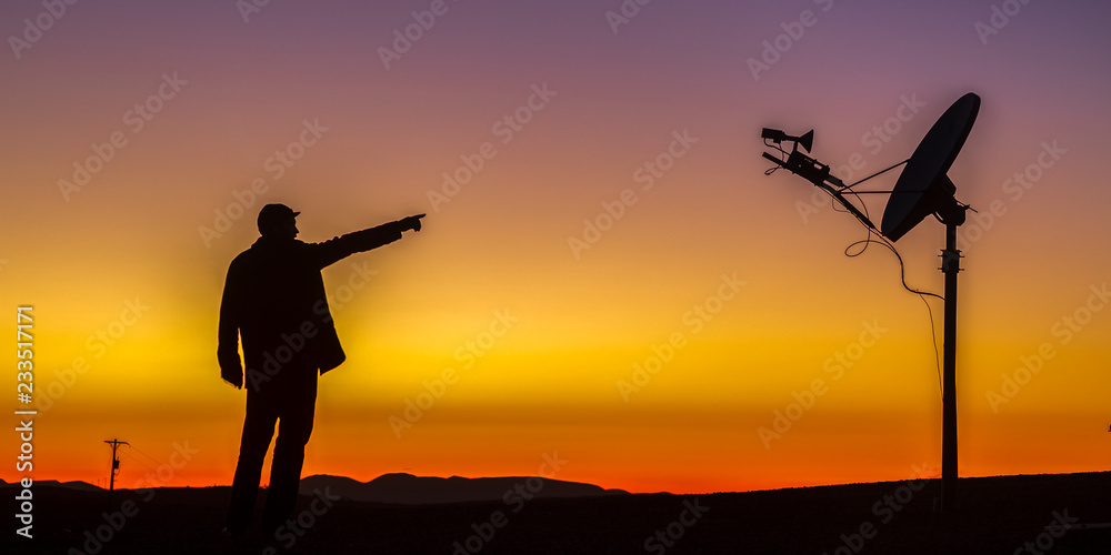Man pointing at satellite against a golden horizon
