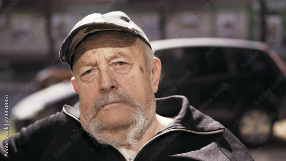 Lonely old man with some sadness and holds on his gray long mustaches at camera Lonely old man with some sadness and holds on his gray long mustaches at camera