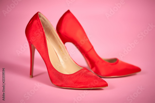 beautiful, satin red high heels on a light pink background