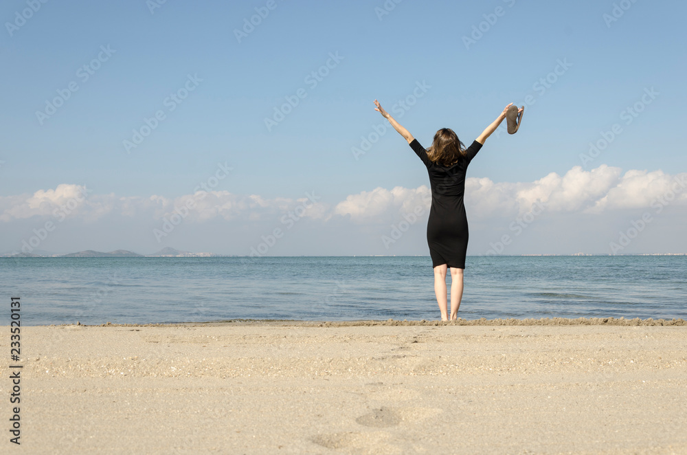 Woman standing with arms outstretched on the beach at sea Woman standing with arms outstretched on the beach at sea