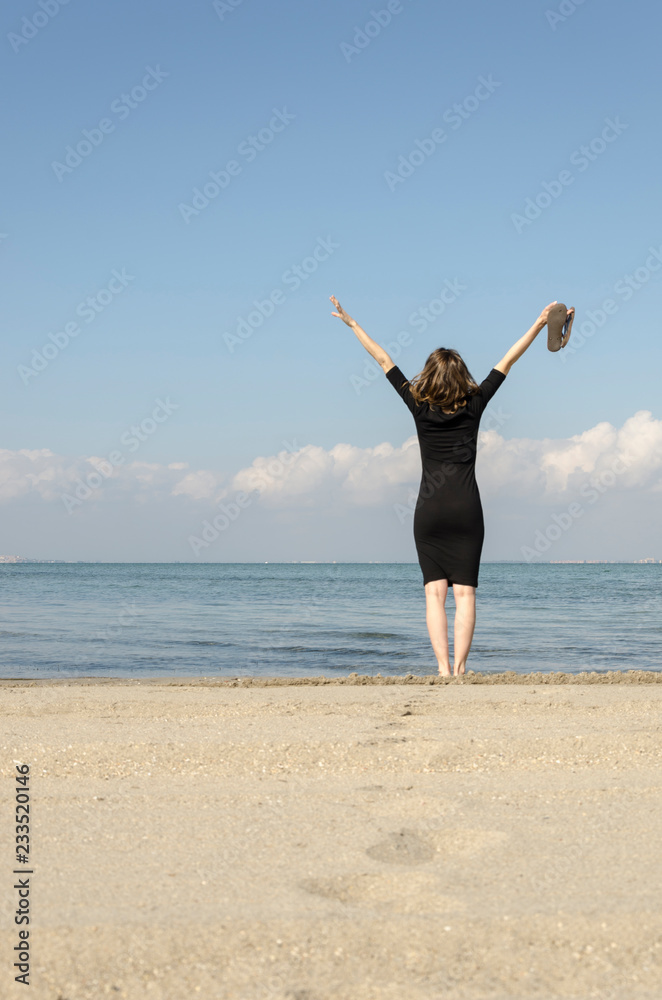 Woman standing with arms outstretched on the beach at sea Woman standing with arms outstretched on the beach at sea