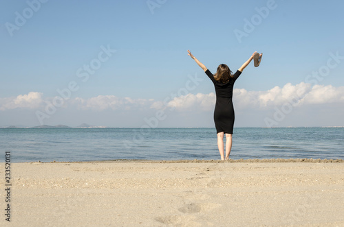 Woman standing with arms outstretched on the beach at sea