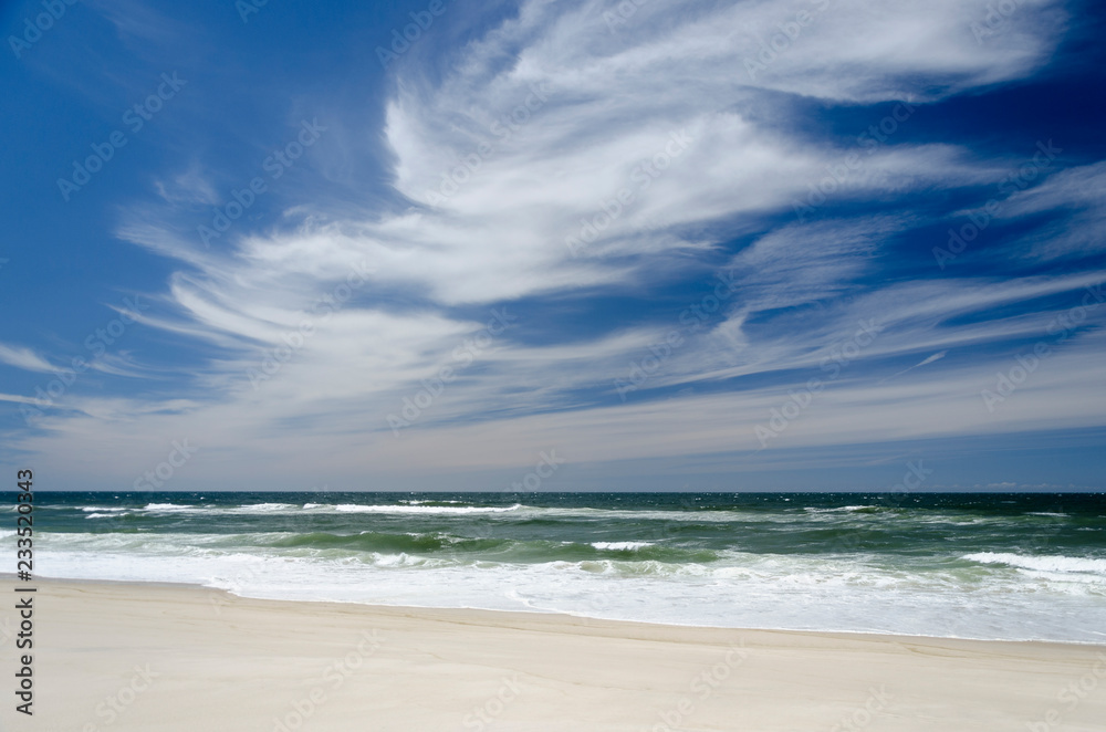 Landscape with a white sand beach and with a dark blue and white sky