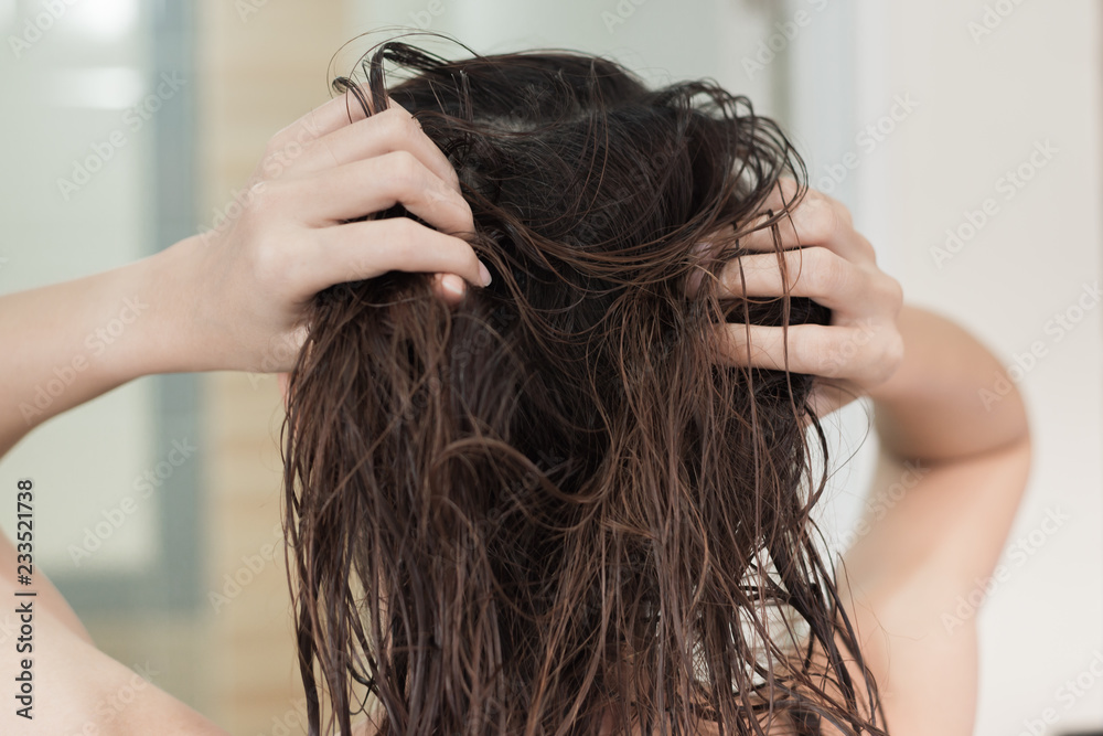 Naklejka premium Rear view of a young asian woman with wet hair after showering.