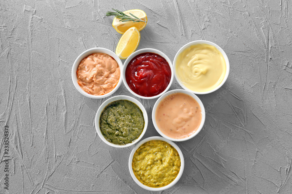 Different tasty sauces in bowls on grey background Different tasty sauces in bowls on grey background