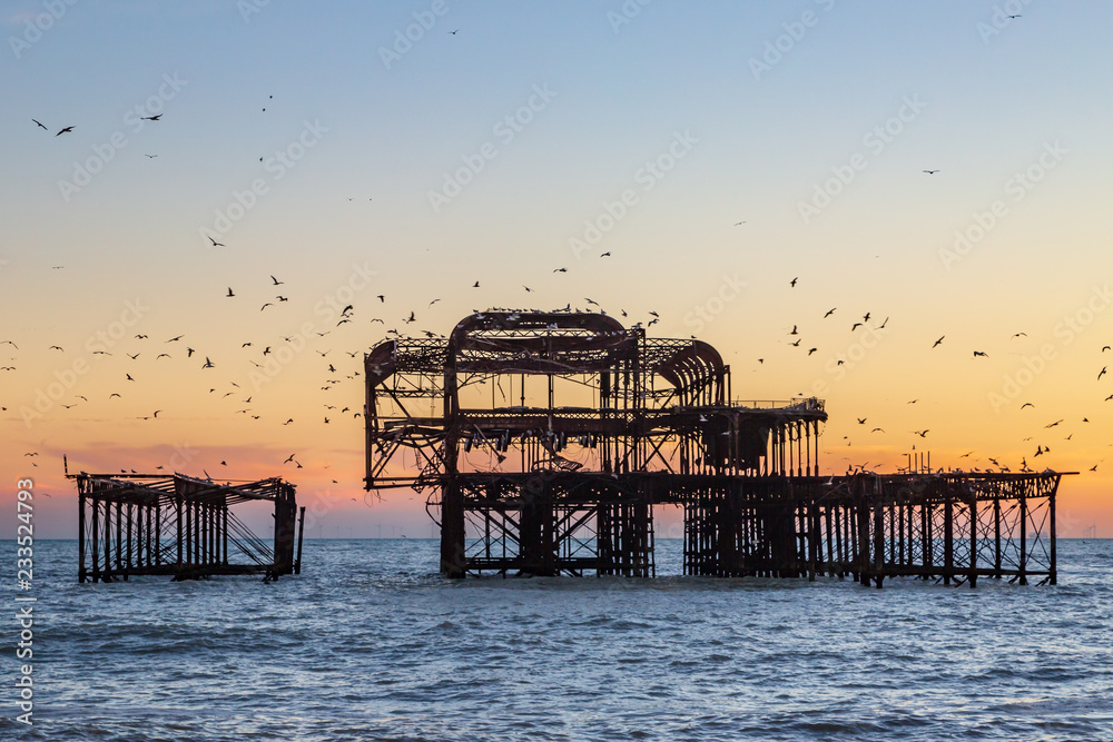 Birds flocking round Brighton's old West Pier at sunset