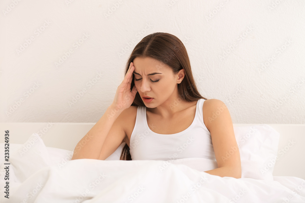 Woman suffering from headache in bedroom Woman suffering from headache in bedroom