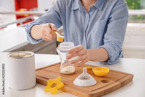 Woman preparing baby formula at table