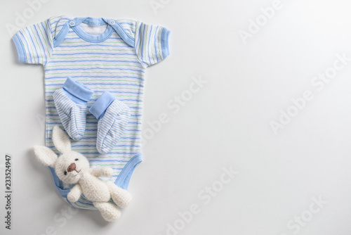 Cute baby clothes and toy on white background