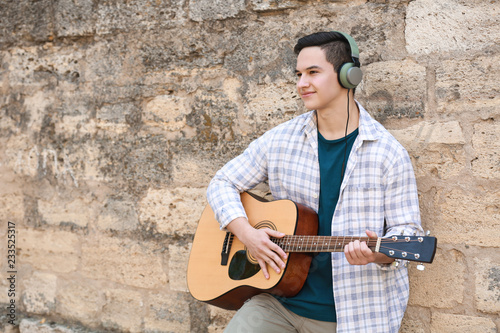 Young man playing guitar ou...