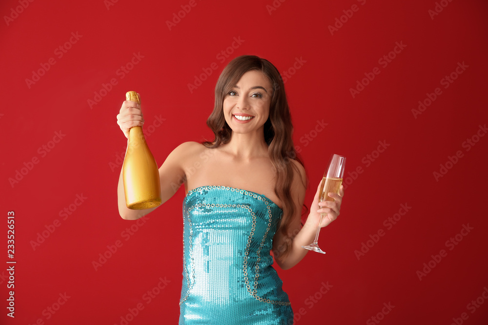 Beautiful young woman with glass and bottle of champagne on color background