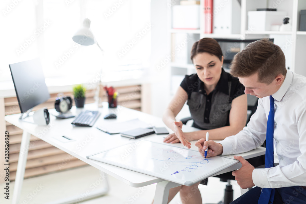 Young people in the office discussing the schedule on a magnetic Board. Young people in the office discussing the schedule on a magnetic Board.