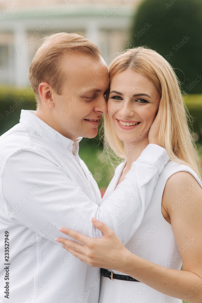 Partrait of man and woman wearing white clothes. Green background. Blond hair woman smile. Lovestory