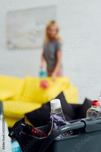 housecleaning supplies in box with woman at background