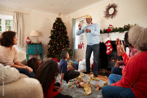 Multi Generation Family Playing Game Of Charades As They Celebrate Christmas At Home Together photo