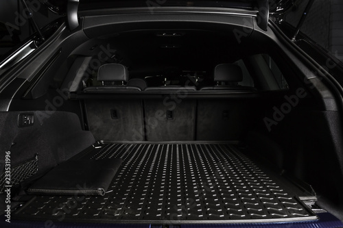 The big black empty trunk of SUV car with rubber mat and with leather folder on the floor  Open luggage carrier of car closeup