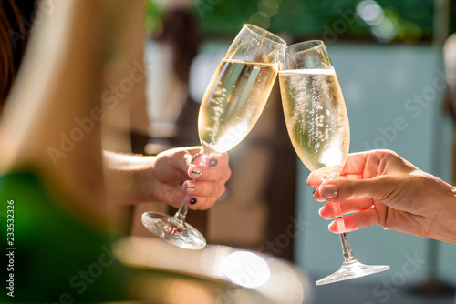 Print op canvas two girls clink glasses of champagne on a beautiful summer terrace