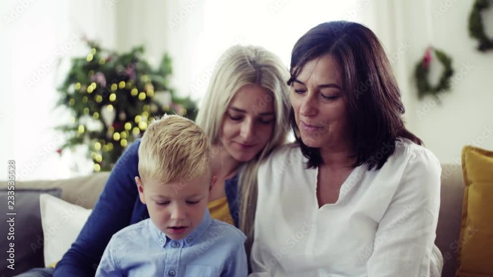 A small boy with mother and grandmother at home at Christmas time, using tablet. A small boy with mother and grandmother at home at Christmas time, using tablet.