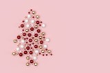 Minimal christmas background composition. Christmas tree with scattered red, gold, white decoration balls and stars on pastel pink background. 3D rendering.