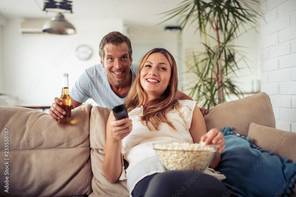 Cheerful couple watching tv together