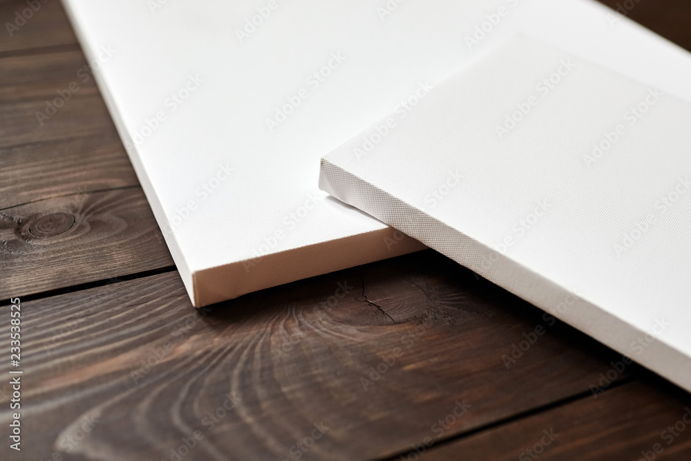 Two white blank canvases on brown wooden background. Mockup Two white blank canvases on brown wooden background. Mockup