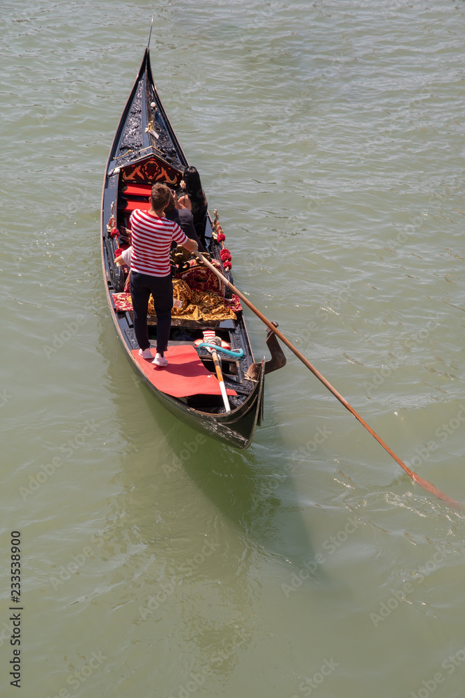 View from above of a gondola on the Grand Canal in Venice with gondolier and tourists in summer, Italy